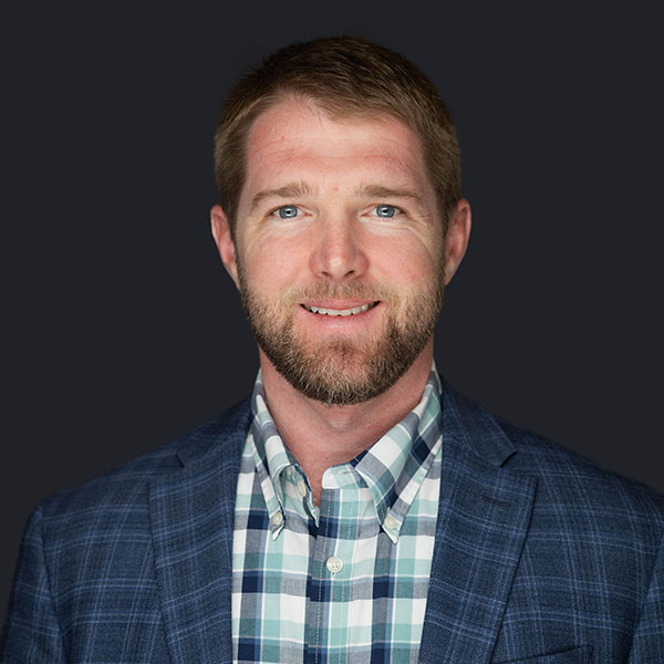 Rob Hotz, General Manager at ECI Contracting, smiling in a plaid shirt and blazer, representing leadership and expertise in underground construction solutions.