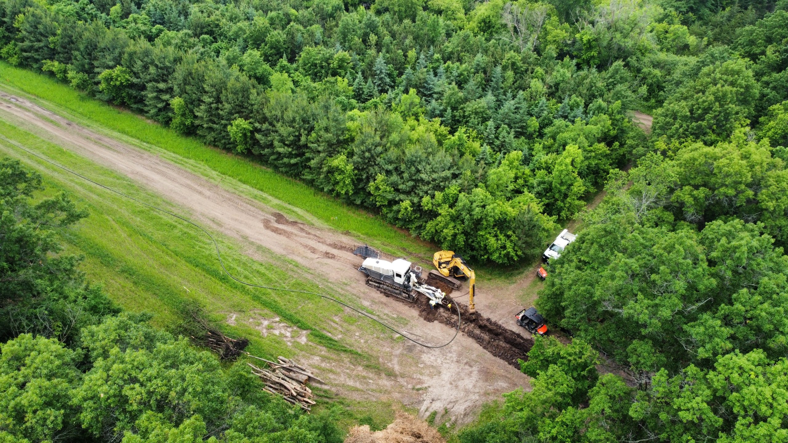 Excavator and plow machinery installing renewable natural gas pipeline in wooded area, emphasizing ECI Contracting's expertise in pipeline construction for RNG projects.