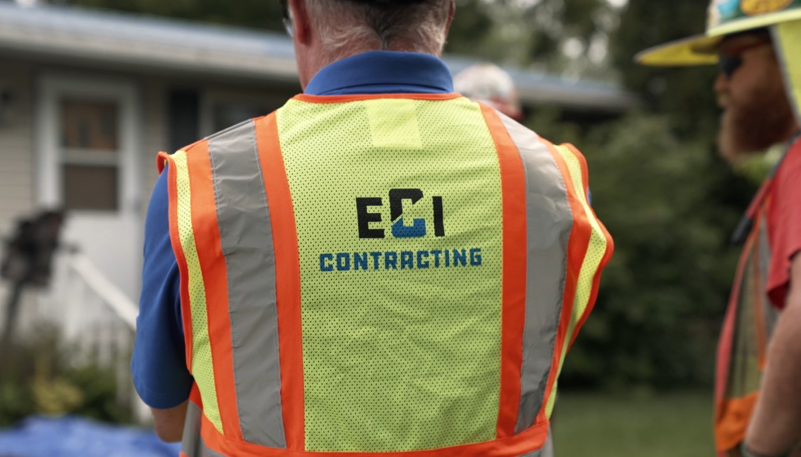 Worker wearing safety vest with "ECI Contracting" logo, emphasizing teamwork and safety in underground infrastructure.