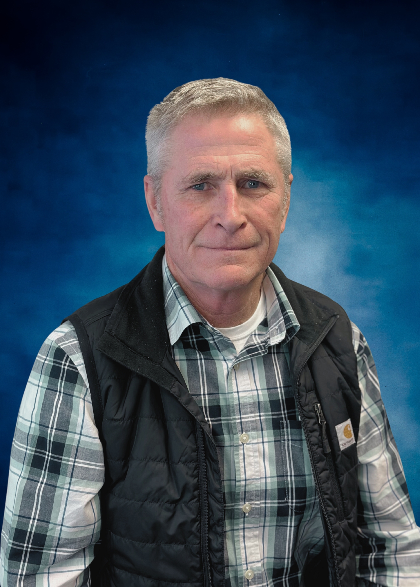 Mike Roussel, Vice President of Operations at ECI Contracting, wearing a plaid shirt and black vest, against a blue background.