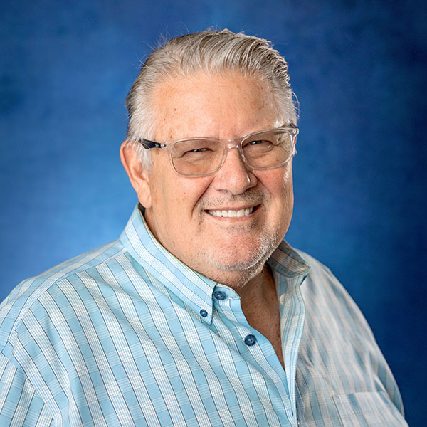 Rob Tumbleson, Director of Sales at ECI Contracting, smiling in a blue background, wearing a light blue striped shirt and glasses.